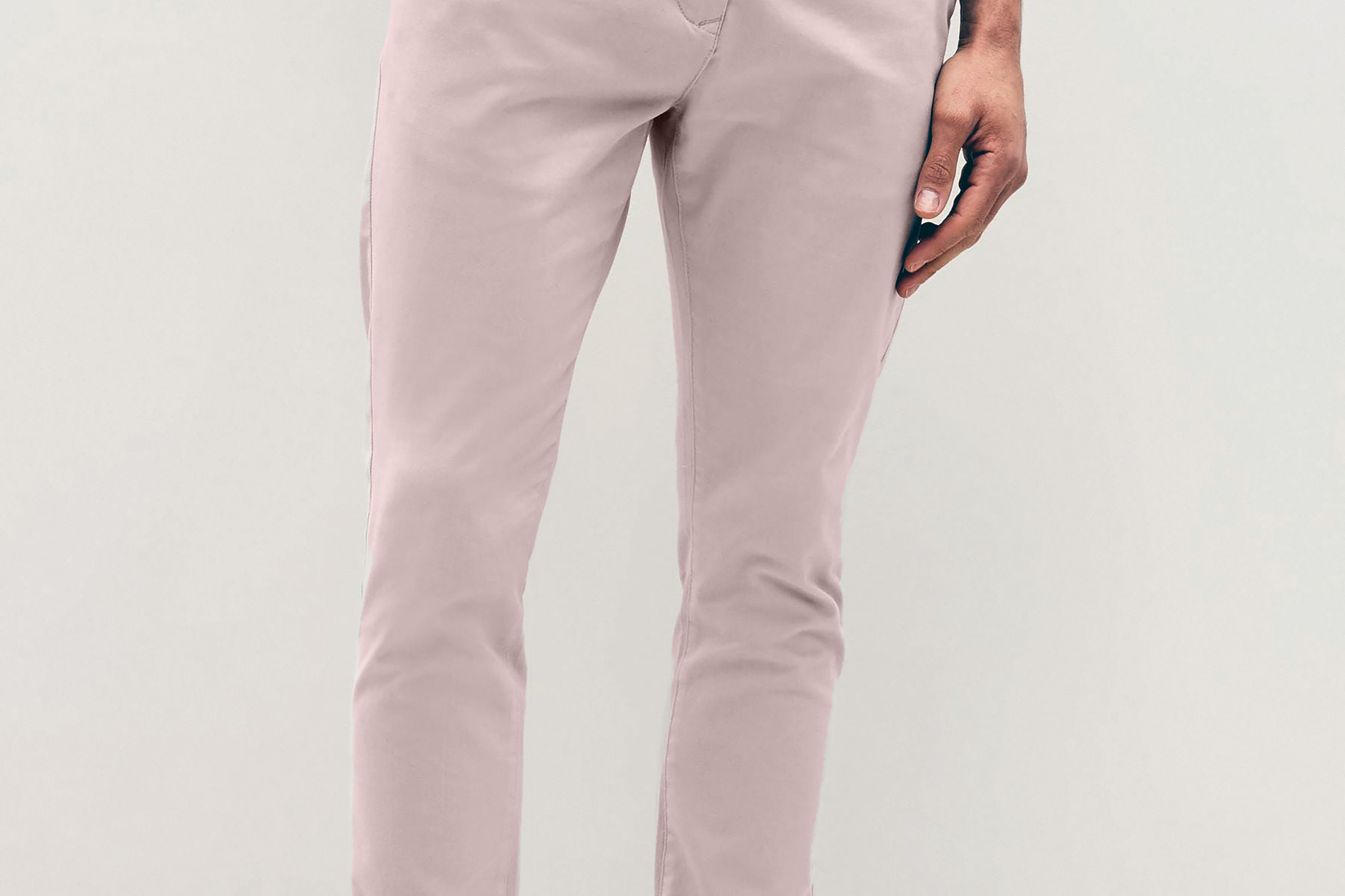 Mens pale pink chinos with front slanted pockets, jetted back pockets. zip fly fastening and brown horne buttons on the waistband and back pockets, the fit is a slim fit, this is worn with a white tee and white unbranded trainers