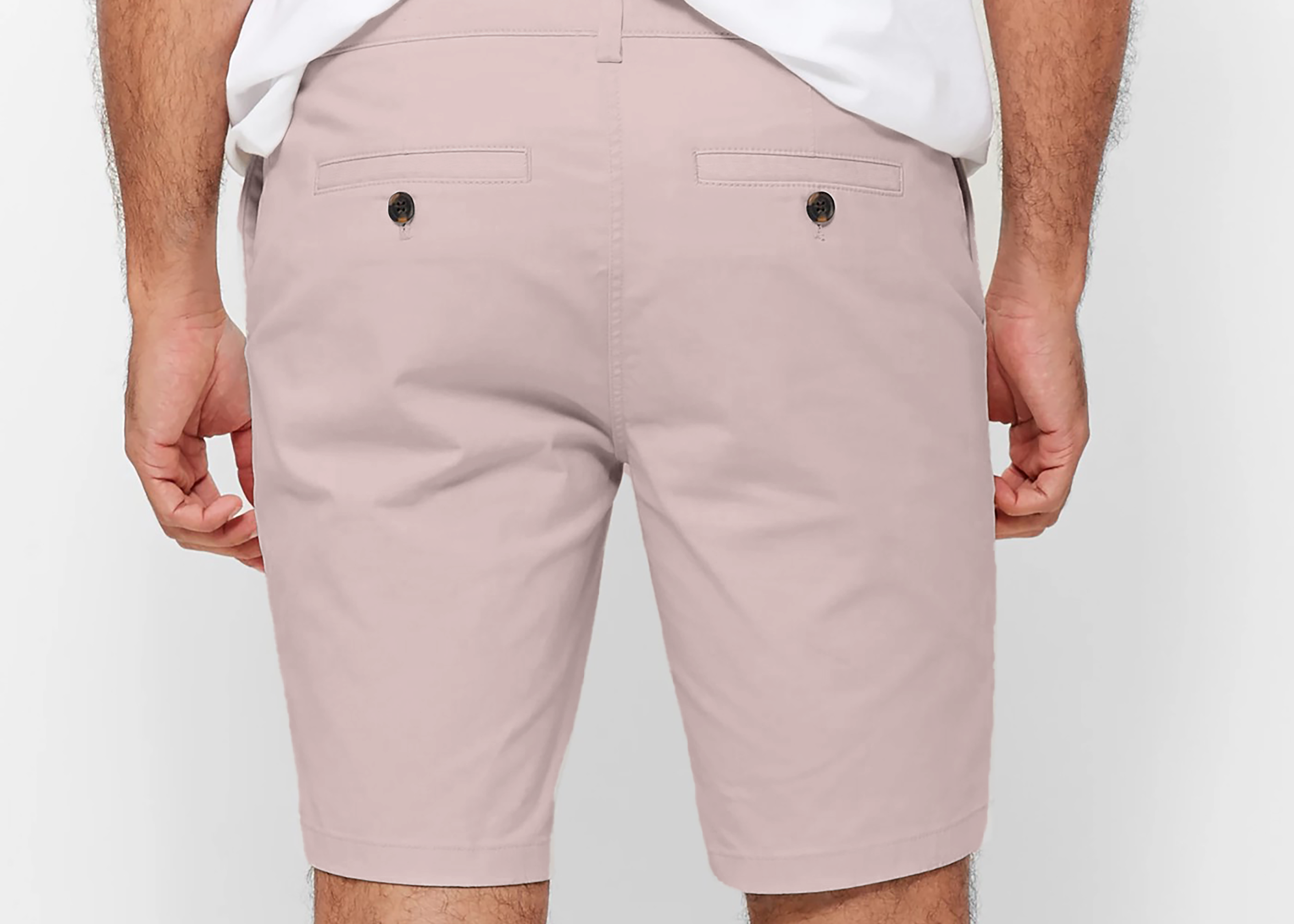 Mens pale pink chinos shorts with front slanted pockets, jetted back pockets. zip fly fastening and brown horne buttons on the waistband and back pockets, the fit is a slim fit, this is worn with a white tee and white t-shirt